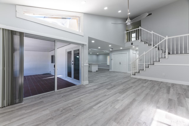 interior space featuring a high ceiling, ceiling fan, and light hardwood / wood-style floors