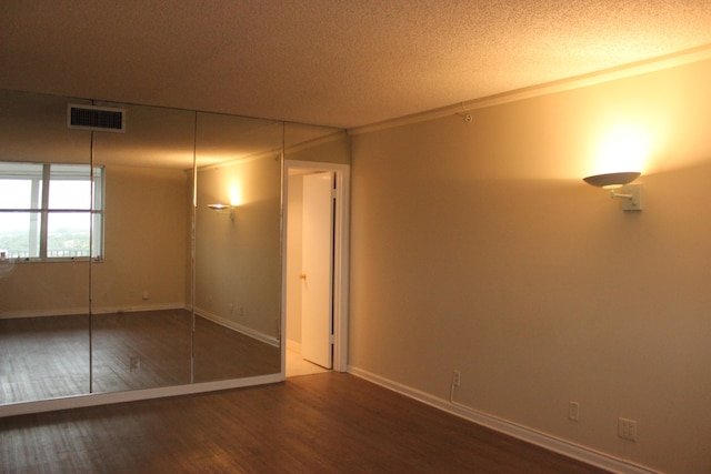 unfurnished bedroom with dark wood-type flooring, a closet, crown molding, and a textured ceiling