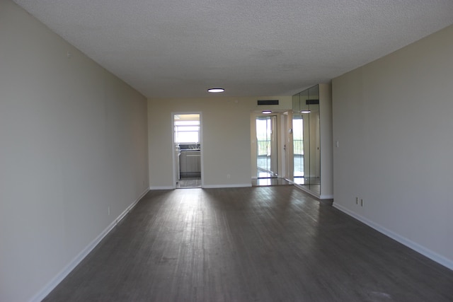 empty room with dark hardwood / wood-style flooring and a textured ceiling