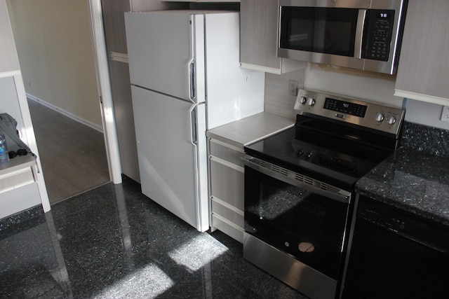 kitchen featuring stainless steel appliances and dark stone counters