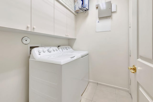 clothes washing area with independent washer and dryer, light tile patterned floors, and cabinets