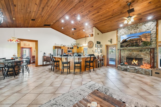 dining room with a stone fireplace, plenty of natural light, light tile patterned floors, and wooden ceiling