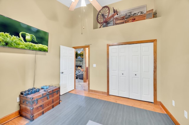 bedroom featuring ceiling fan, a closet, a high ceiling, and hardwood / wood-style flooring