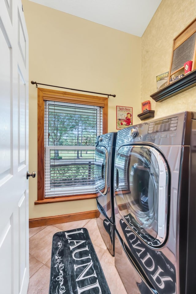 clothes washing area with washing machine and dryer and light tile patterned floors