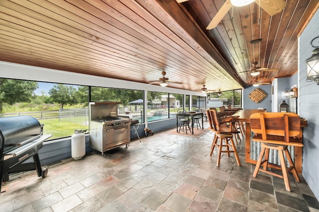 sunroom / solarium with ceiling fan and wood ceiling