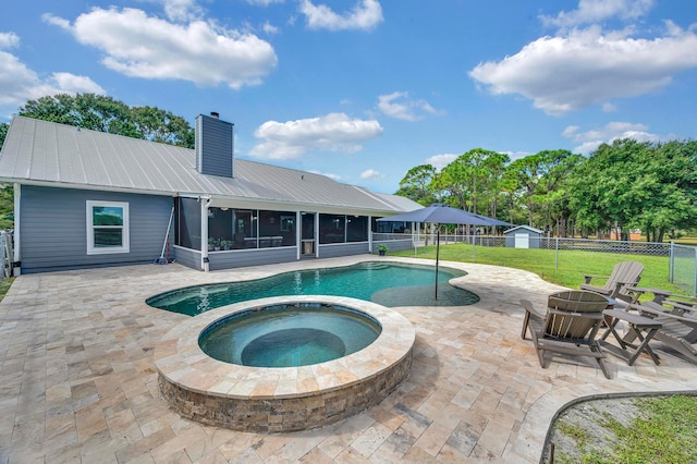 view of swimming pool with a lawn, a sunroom, an outdoor fire pit, a patio area, and an in ground hot tub