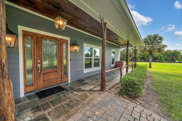 entrance to property featuring a lawn and covered porch