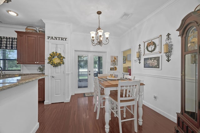 dining room with crown molding, french doors, dark hardwood / wood-style floors, and an inviting chandelier