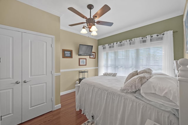 bedroom with dark hardwood / wood-style flooring, ceiling fan, a closet, and ornamental molding