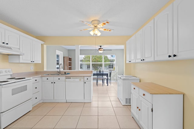 kitchen with white appliances, sink, kitchen peninsula, white cabinets, and light tile patterned floors