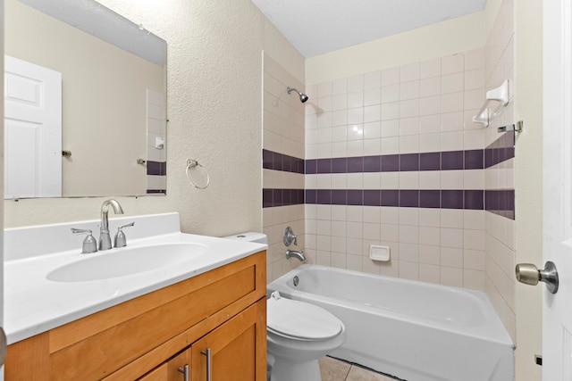 full bathroom featuring tiled shower / bath combo, tile patterned flooring, a textured ceiling, toilet, and vanity