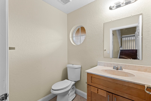 bathroom featuring tile patterned floors, vanity, a textured ceiling, and toilet