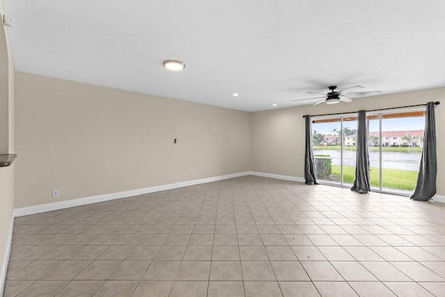 spare room with ceiling fan, a water view, and light tile patterned floors