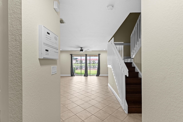 staircase featuring tile patterned floors and ceiling fan