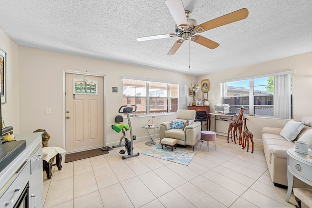 tiled living room with ceiling fan, a textured ceiling, and a wealth of natural light