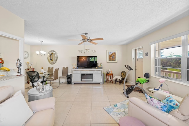 living room featuring a textured ceiling, light tile patterned floors, and ceiling fan with notable chandelier