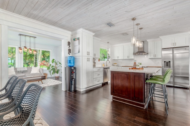 kitchen with stainless steel appliances, wall chimney range hood, dark hardwood / wood-style flooring, and white cabinetry