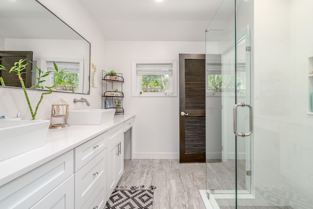 bathroom with wood-type flooring, vanity, and a shower with shower door