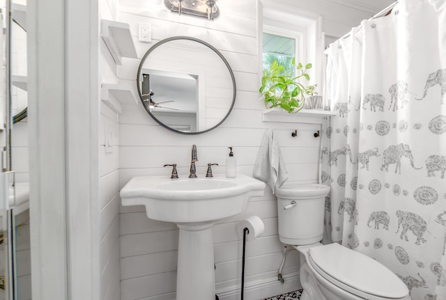 bathroom featuring a shower with curtain, wood walls, and toilet