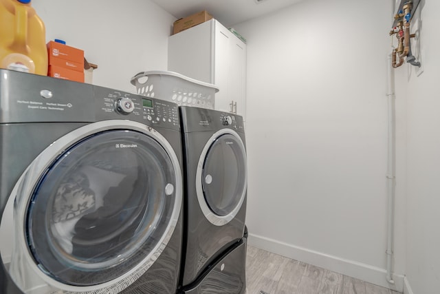 washroom featuring cabinets, light hardwood / wood-style floors, and washing machine and clothes dryer