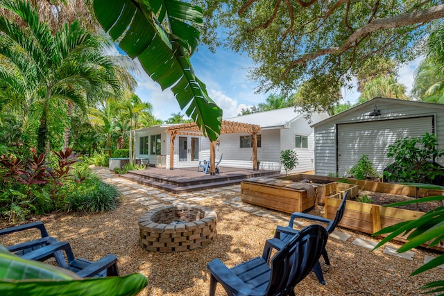 back of house featuring a garage, a patio area, a pergola, an outdoor fire pit, and an outdoor structure