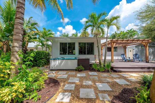 back of house featuring a wooden deck, a hot tub, and a pergola