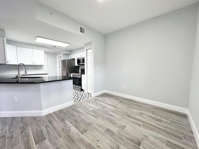 kitchen featuring tasteful backsplash, sink, white cabinetry, light wood-type flooring, and stainless steel appliances