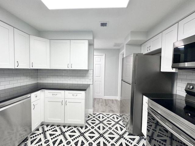 kitchen featuring white cabinets, backsplash, appliances with stainless steel finishes, and light hardwood / wood-style floors