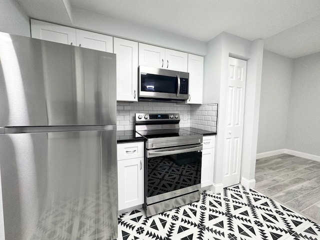 kitchen with decorative backsplash, white cabinets, appliances with stainless steel finishes, and light hardwood / wood-style flooring