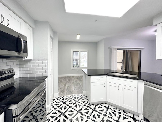 kitchen with kitchen peninsula, stainless steel appliances, decorative backsplash, white cabinets, and sink