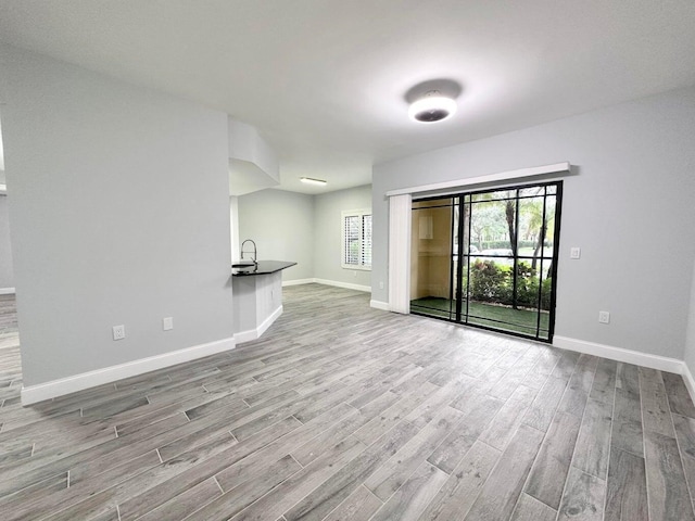 unfurnished living room with sink and light hardwood / wood-style flooring