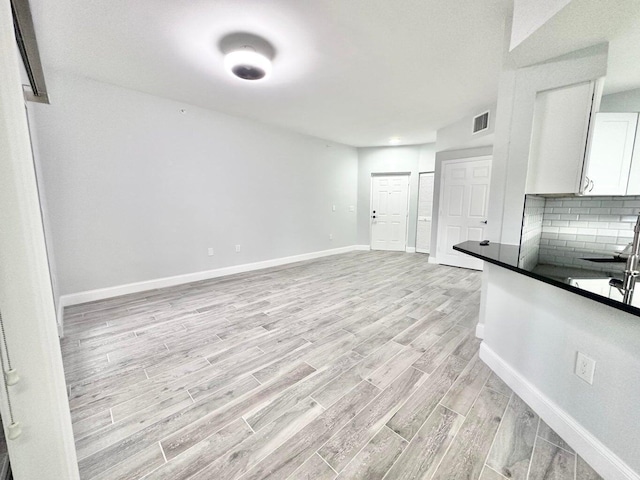 interior space featuring light hardwood / wood-style flooring, backsplash, and white cabinets