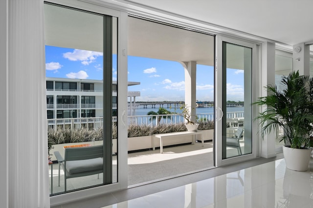 doorway featuring tile patterned floors, floor to ceiling windows, and a water view