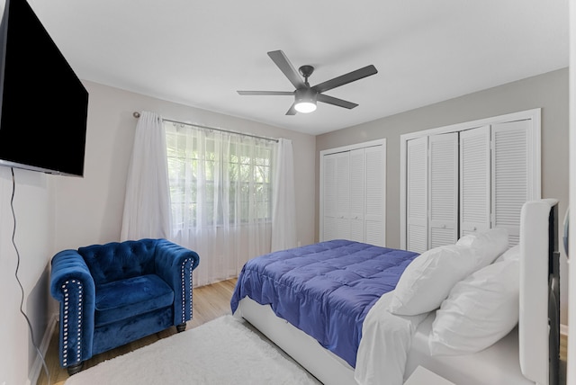 bedroom with ceiling fan, multiple closets, and hardwood / wood-style floors