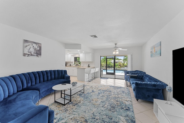 tiled living room with a textured ceiling and ceiling fan