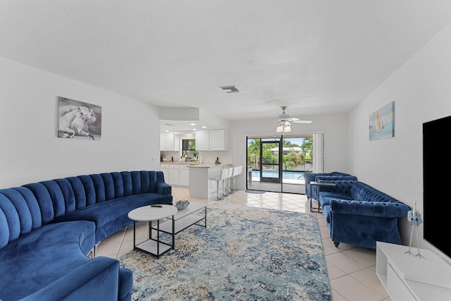 tiled living room with ceiling fan and a textured ceiling