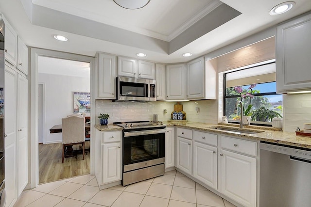 kitchen featuring appliances with stainless steel finishes, a raised ceiling, sink, and white cabinetry