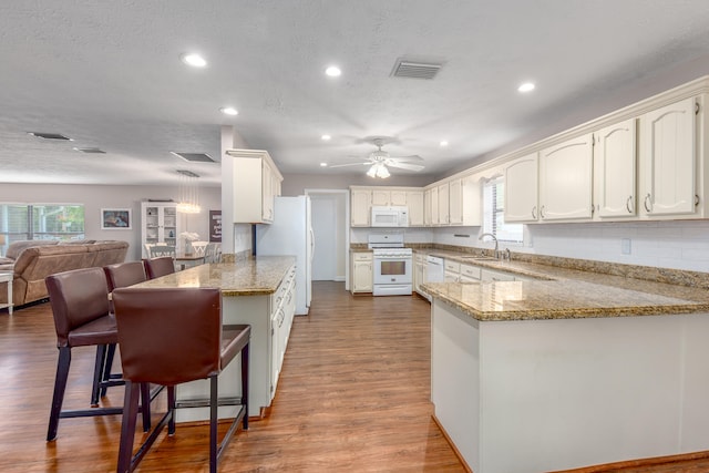 kitchen featuring kitchen peninsula, a healthy amount of sunlight, and white appliances