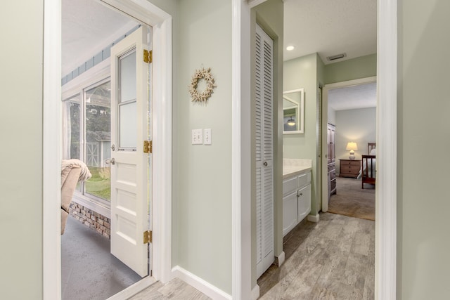 corridor featuring light hardwood / wood-style floors and a textured ceiling