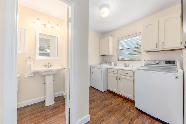 clothes washing area with sink, dark hardwood / wood-style floors, cabinets, and washer and clothes dryer