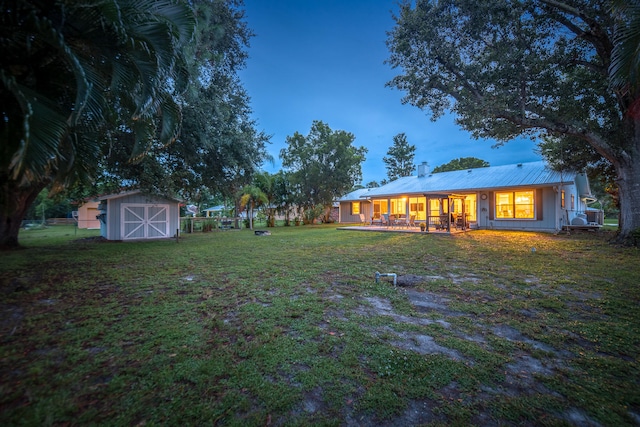 yard at dusk featuring covered porch and a storage unit