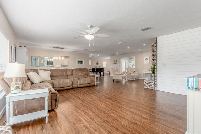 living room with wood-type flooring, wooden walls, a textured ceiling, and ceiling fan