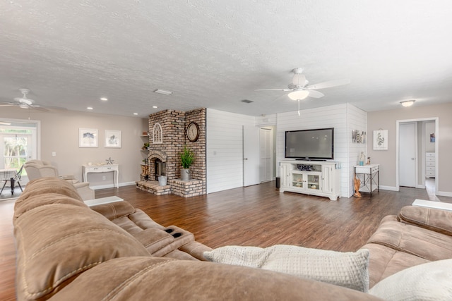 living room featuring ceiling fan, dark wood-type flooring, and a textured ceiling