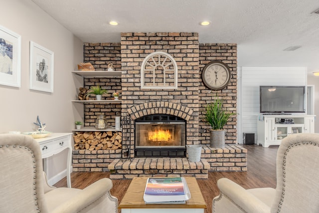 living room featuring a textured ceiling, a fireplace, and hardwood / wood-style floors