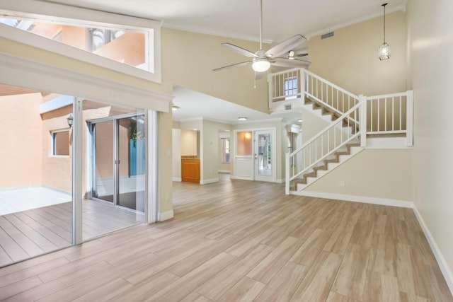 unfurnished living room featuring light hardwood / wood-style flooring, ceiling fan, a high ceiling, and crown molding