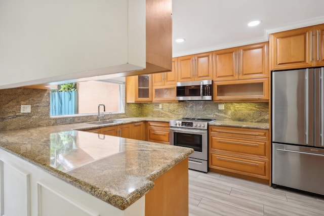 kitchen with light stone counters, stainless steel appliances, sink, and kitchen peninsula