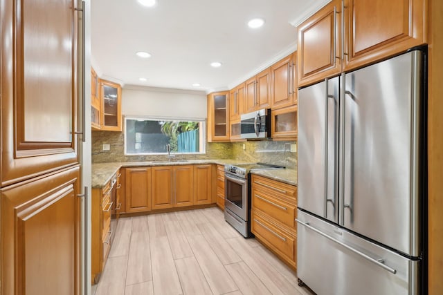 kitchen with stainless steel appliances, sink, light stone counters, and backsplash