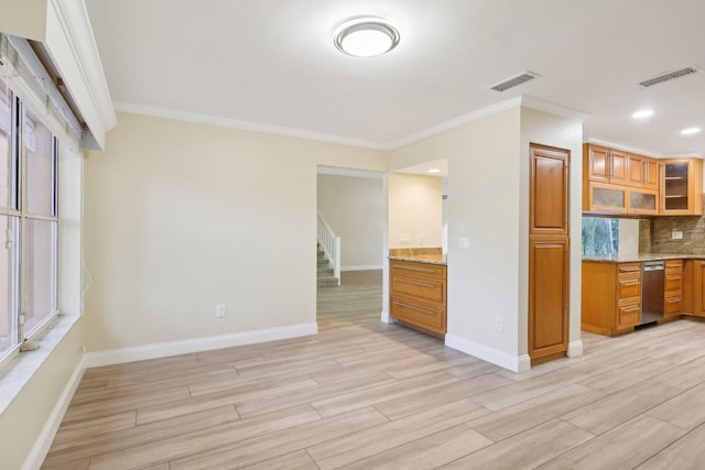 kitchen with ornamental molding, decorative backsplash, light stone counters, and light hardwood / wood-style floors