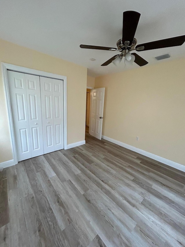 unfurnished bedroom featuring a closet, light hardwood / wood-style flooring, and ceiling fan