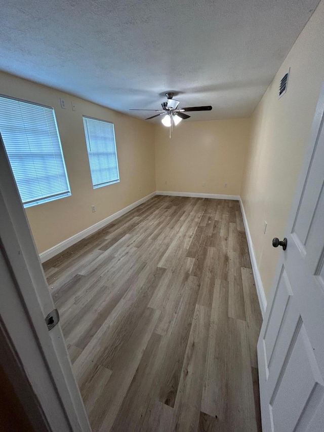 spare room featuring ceiling fan, light hardwood / wood-style floors, and a textured ceiling